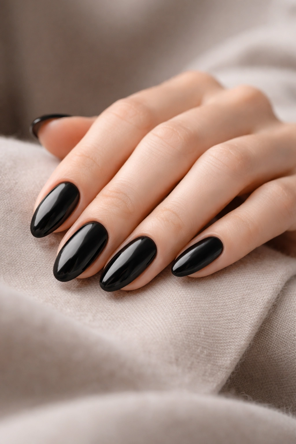 Hand with black oval nails in a thoughtful pose on a neutral surface