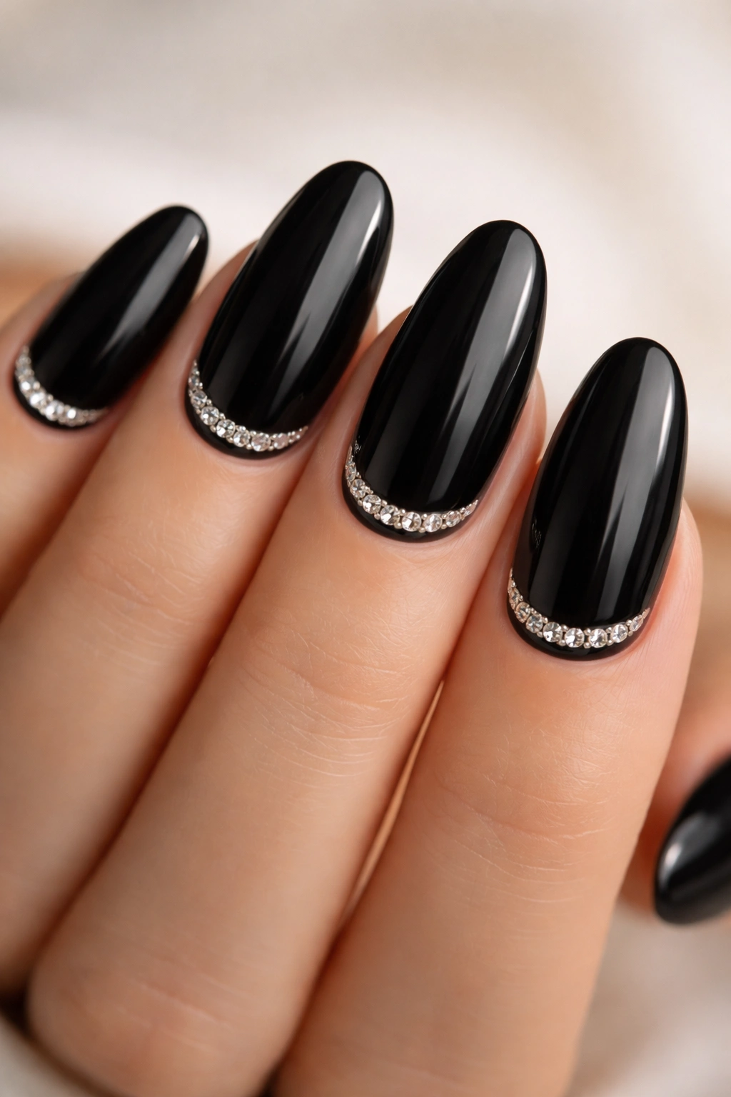 Close-up of long black oval nails with tiny rhinestones near the cuticle