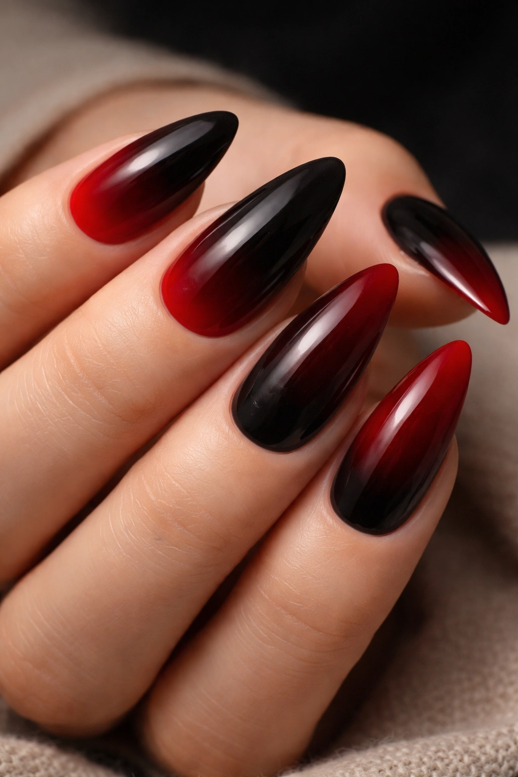 Close-up of black and red nails with ombré gradient and red tips.