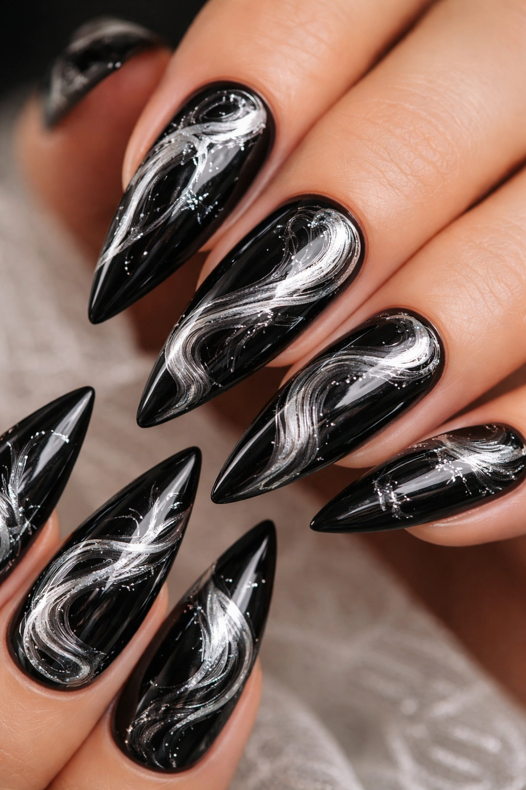 Close-up of glossy black nails with silver marble swirls