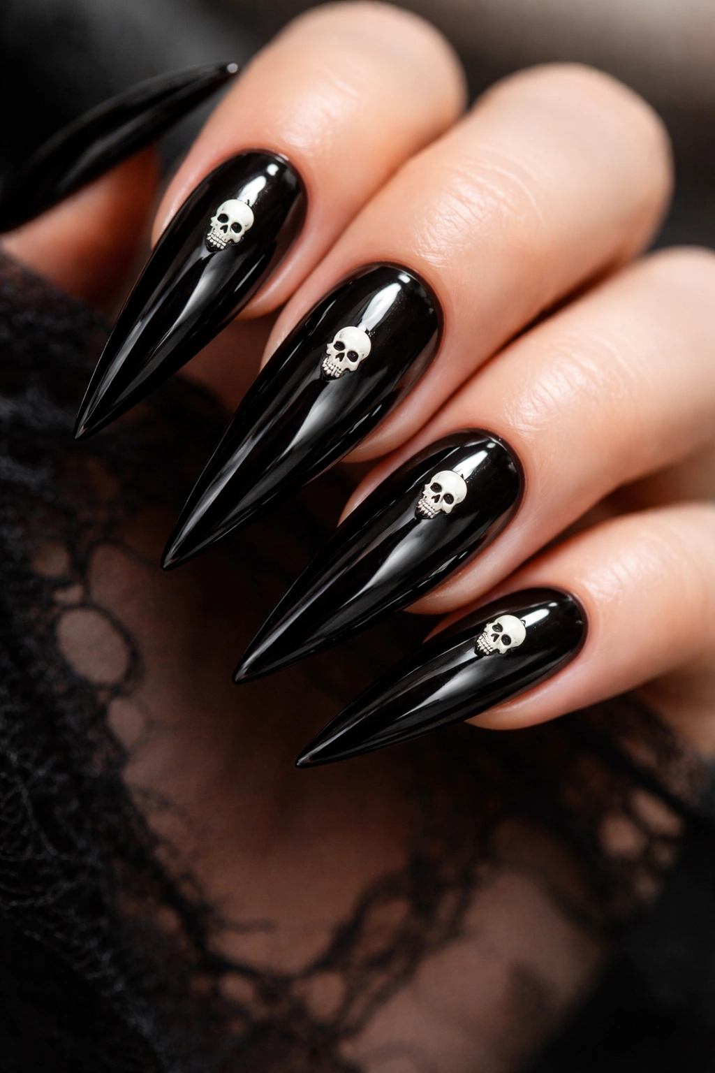 Close-up of glossy black stiletto nails with tiny white skull accents on each nail