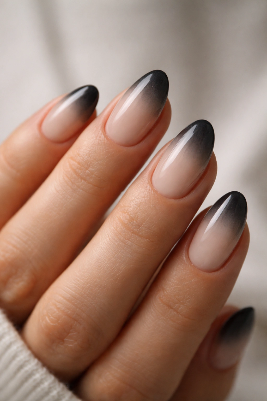 Close-up of short almond nails with a charcoal smoke fade on a milky nude base