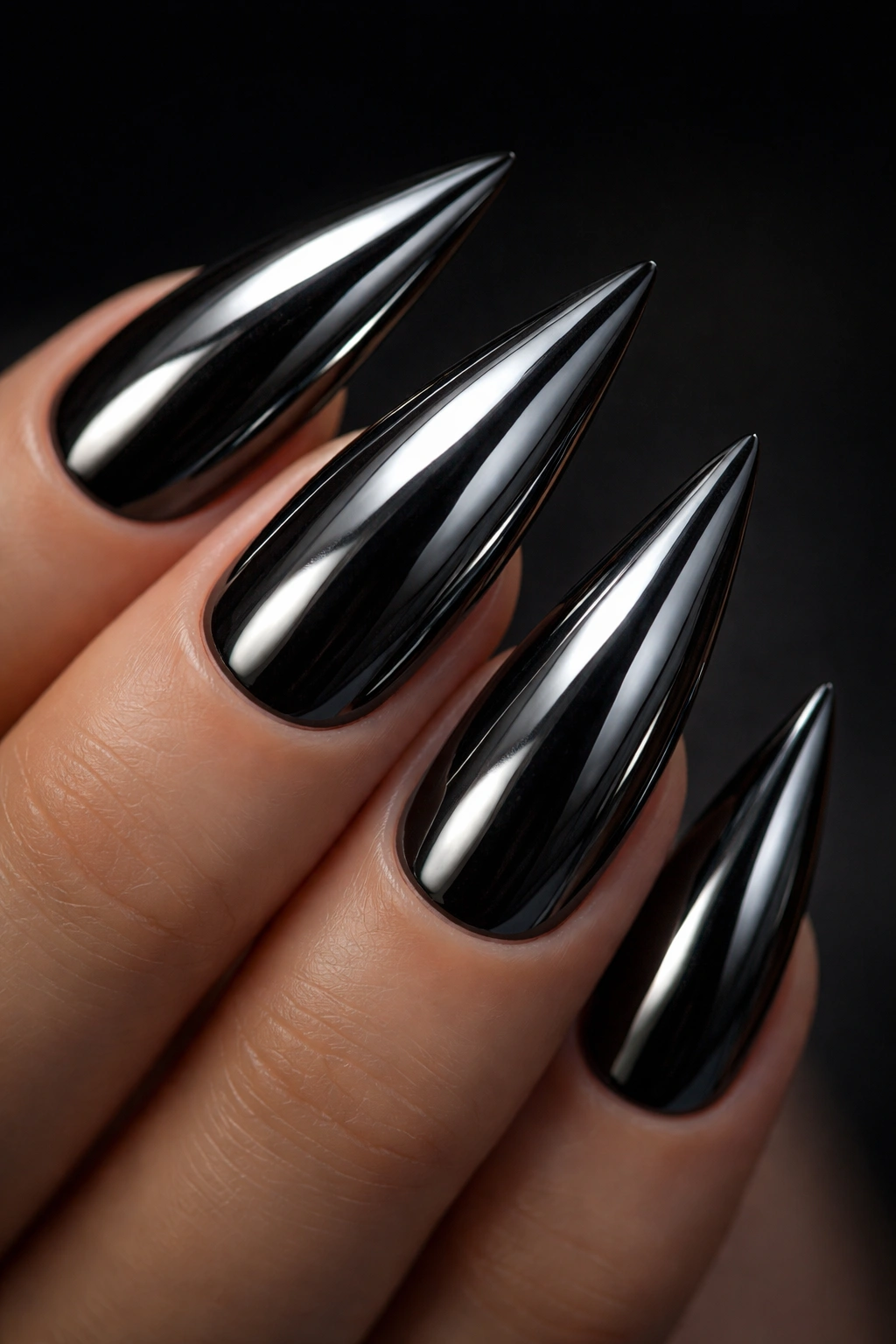 Close-up of black stiletto nail with full chrome powder finish reflecting light