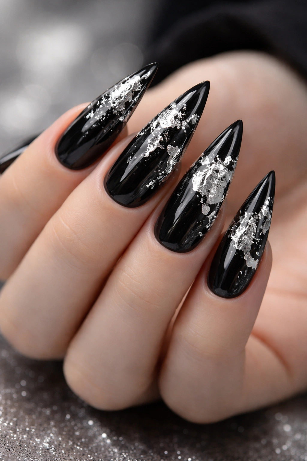 Close-up of black stiletto nails with silver foil accents