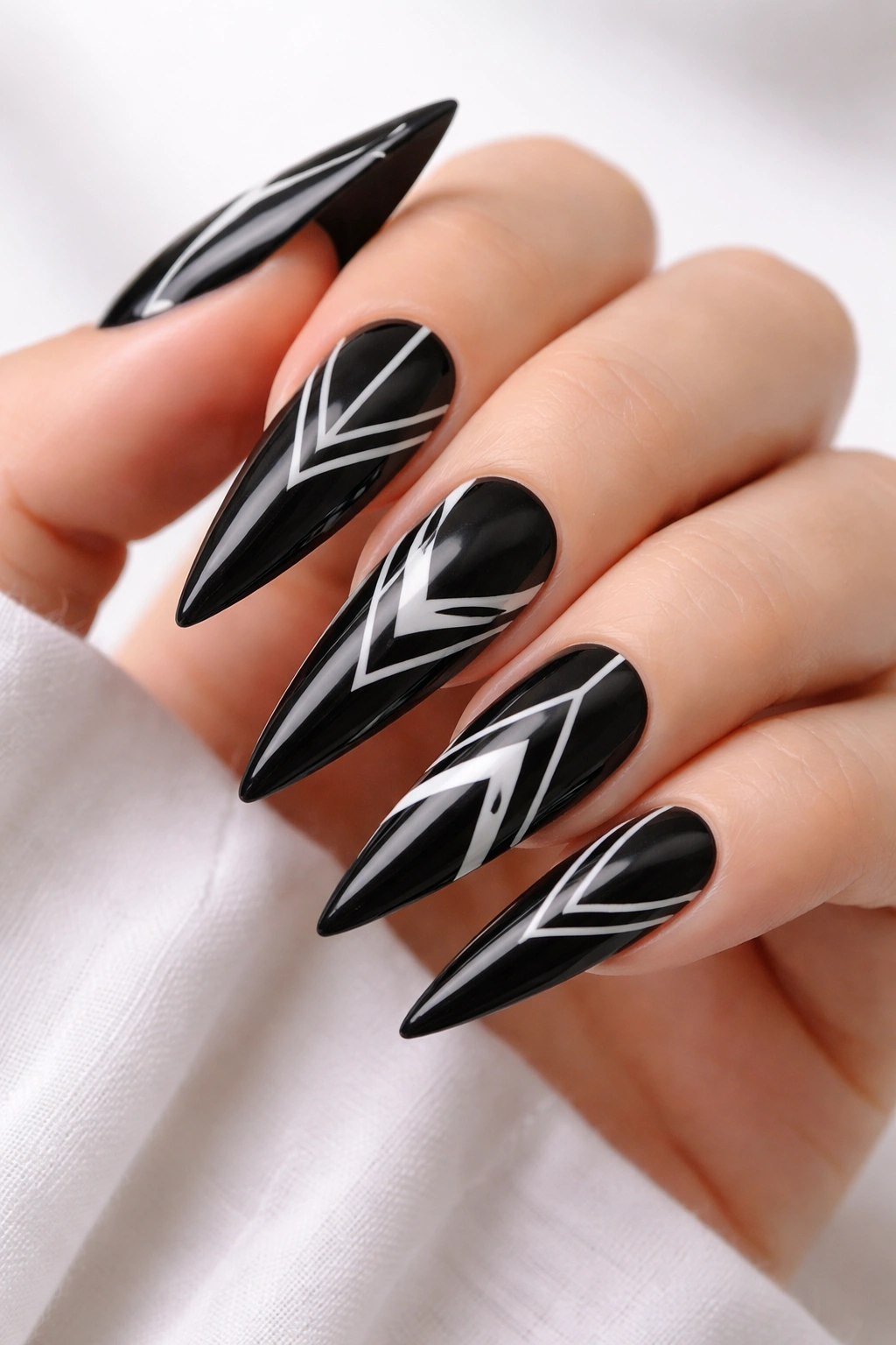 Close-up of black stiletto nails with white geometric line art
