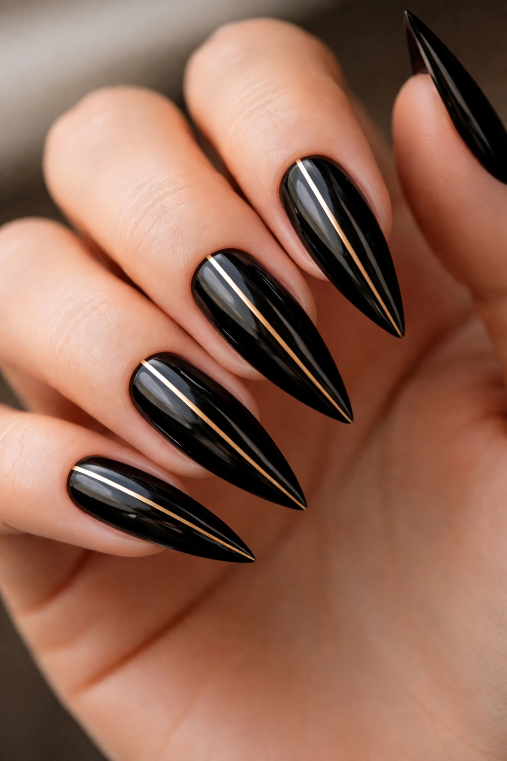 Close-up of black stiletto nails with thin gold striping