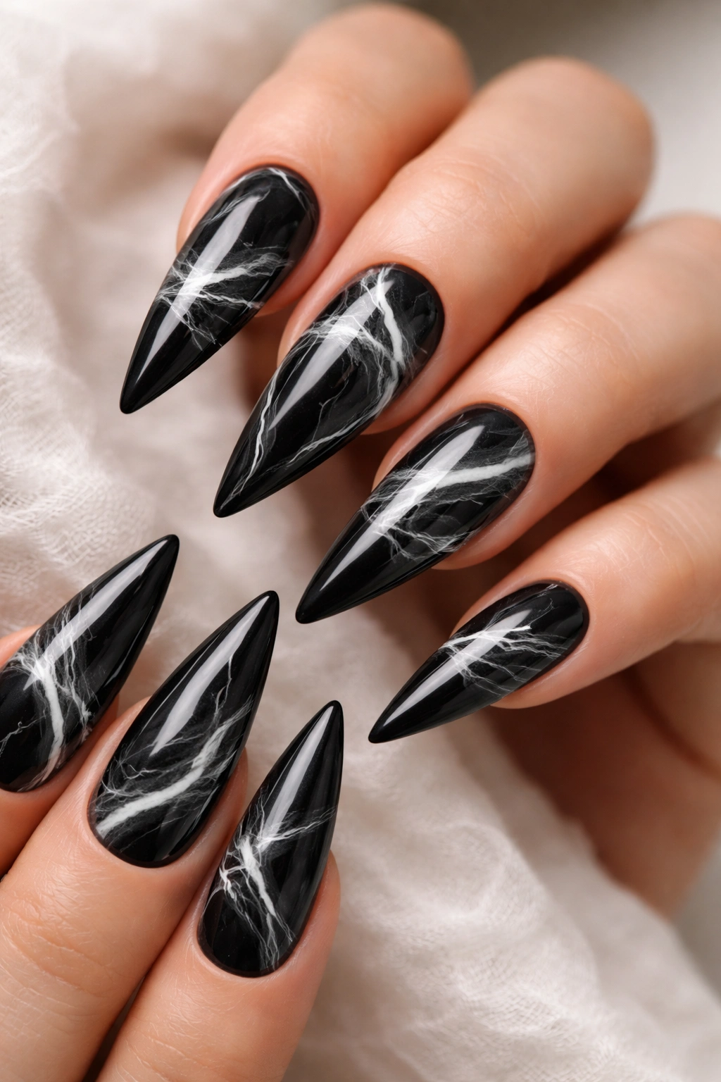 Close-up of black stiletto nails with white marble swirl design
