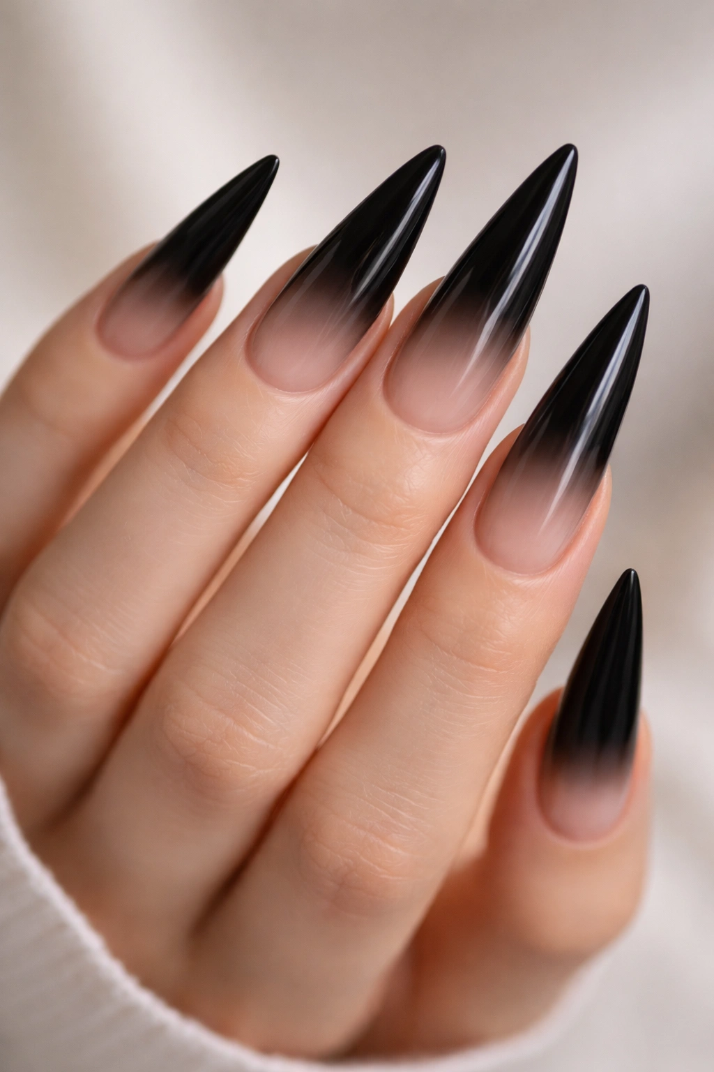 Close-up of long black stiletto nails with nude gradient tips