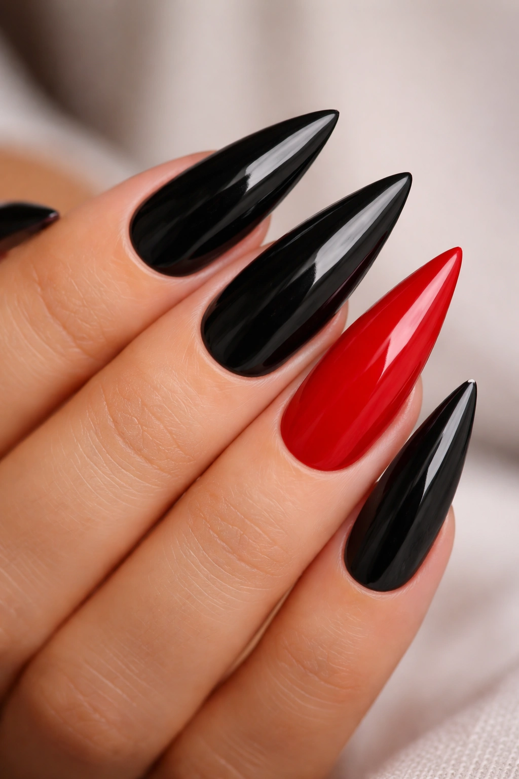 Close-up of black stiletto nails with a single red accent nail