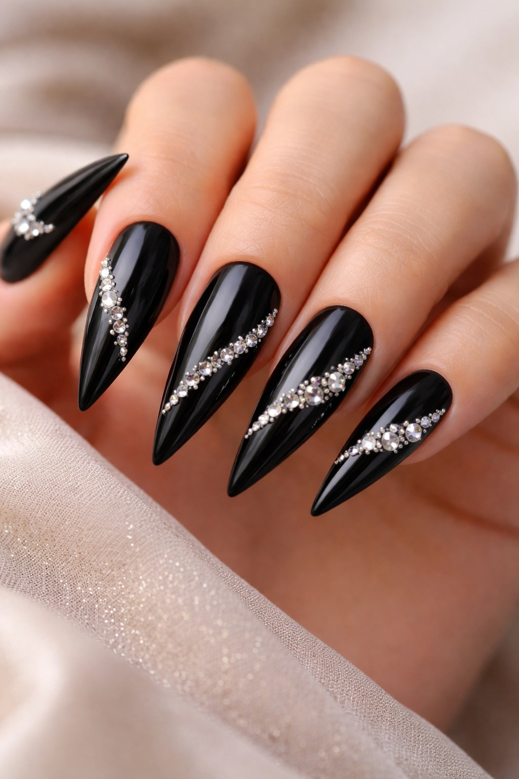Glossy black stiletto nails with rhinestone accents