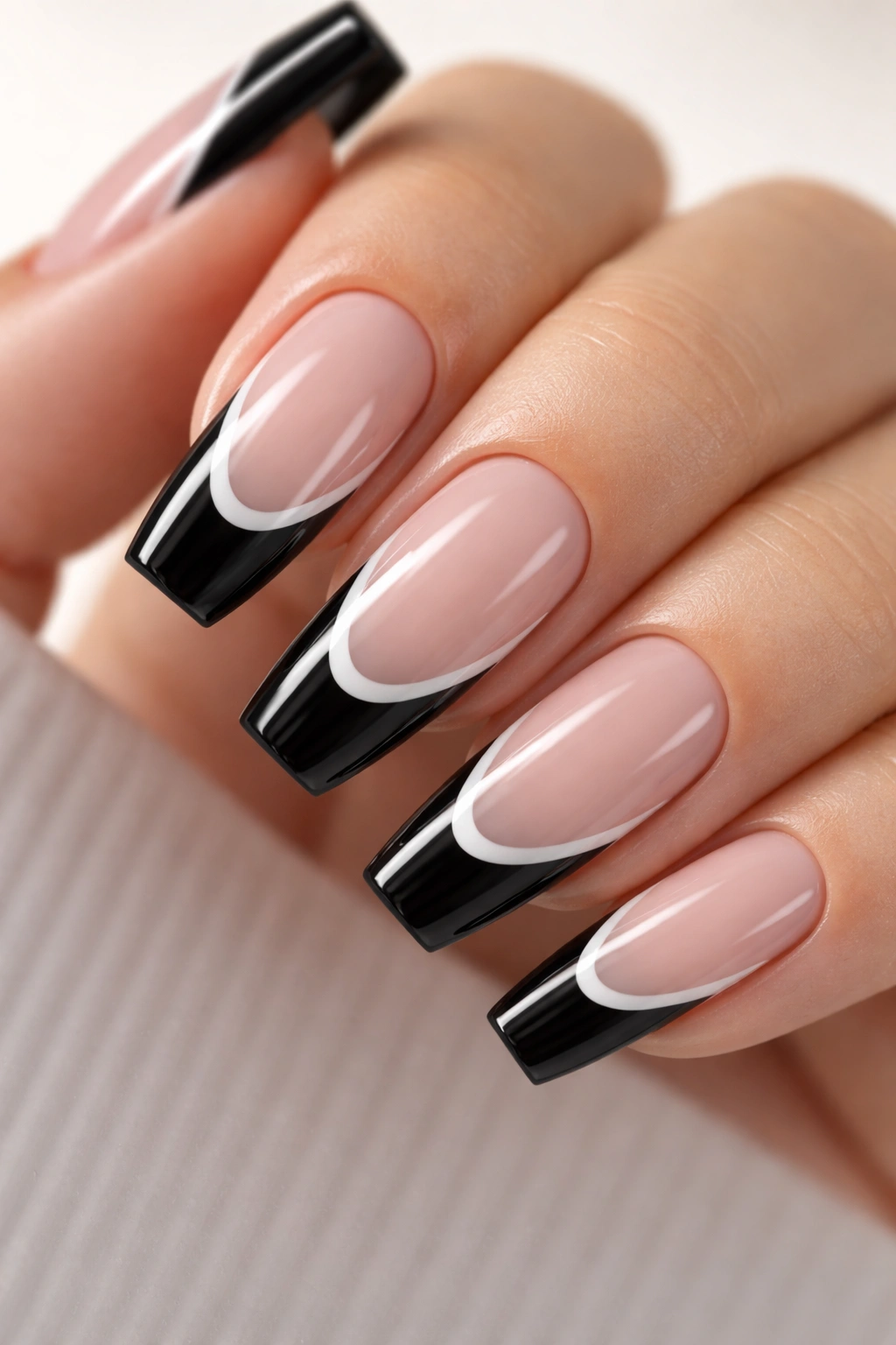 Close-up of black tip with a white line accent on medium coffin nails