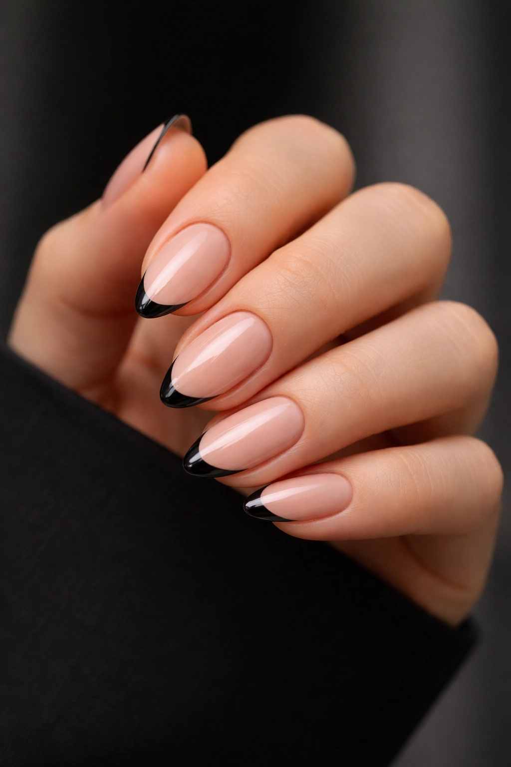 Close-up of short almond nails with thin black tips on nude base