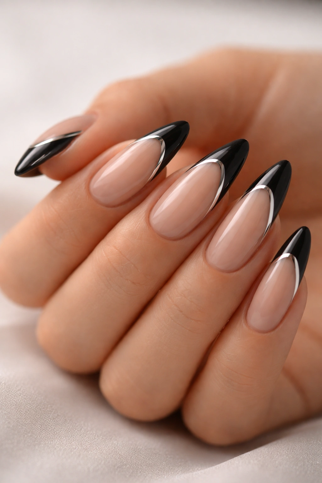 Close-up of almond nails with black tips and a thin chrome edge line.