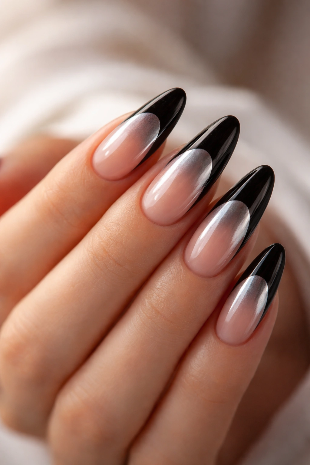 Close-up of long almond nails with black French tips and a chrome underlay.