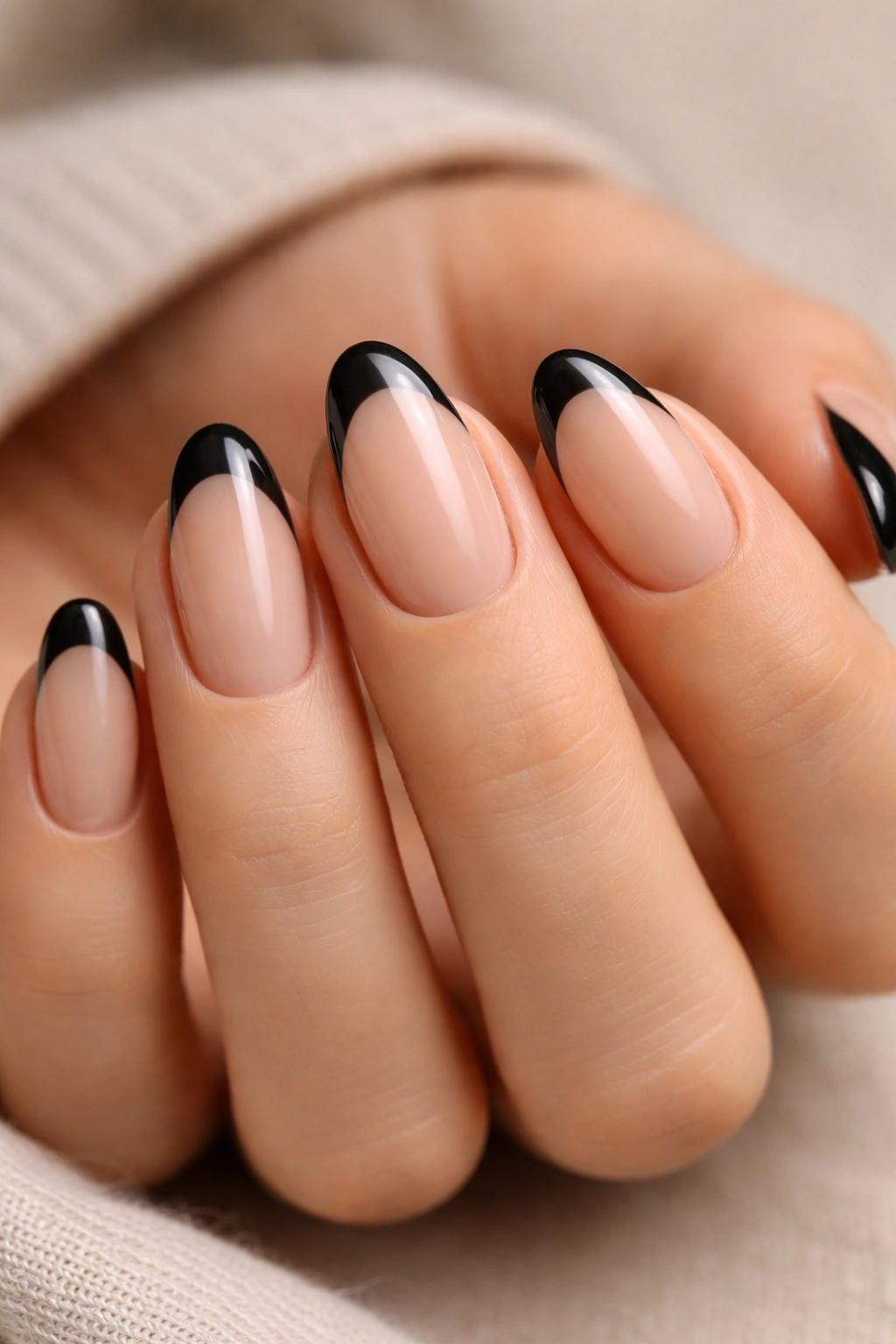 Close-up of short almond nails with sheer nude base and black tips