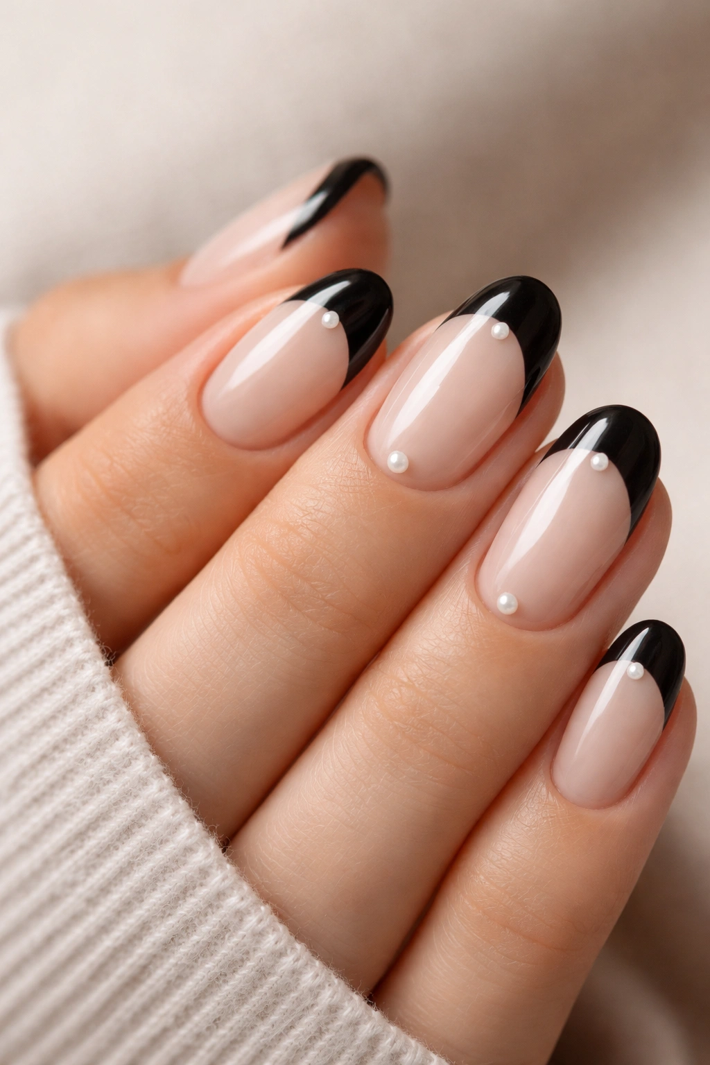 Close-up of short oval nails with black tips and a tiny pearl near the cuticle.