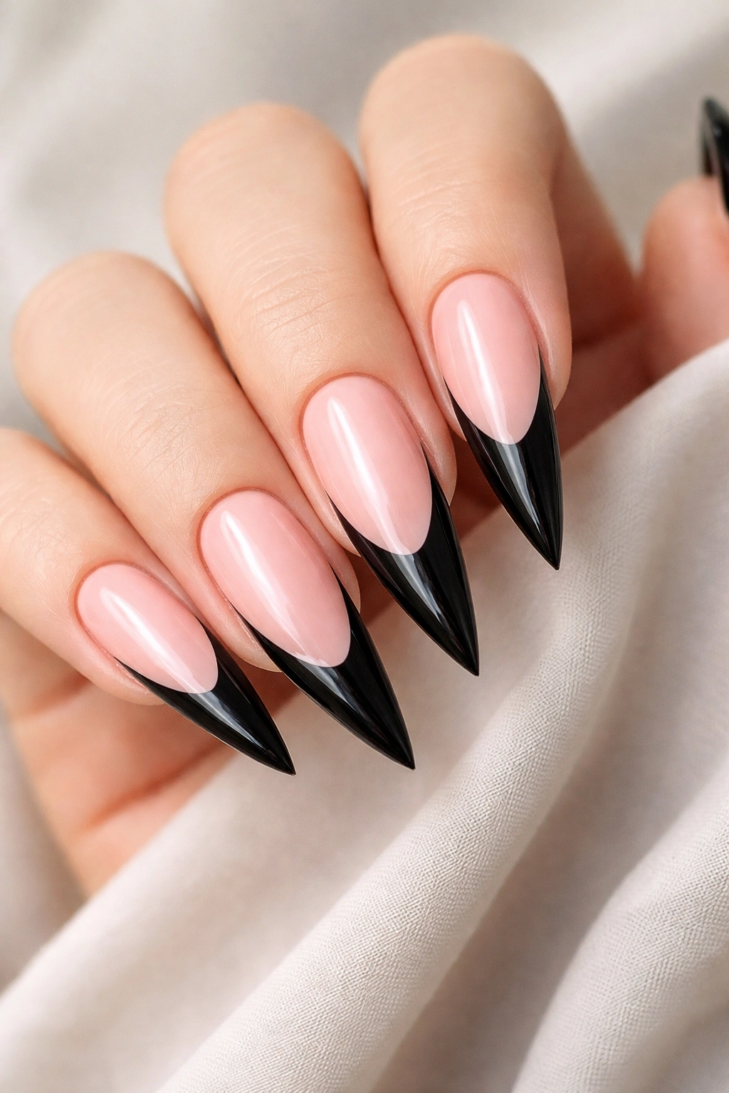 Close-up of stiletto nails with black tips on pink base