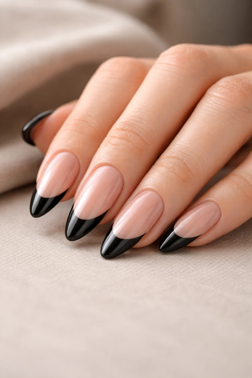 Close-up of almond nails with glossy black tips and flawless finish.