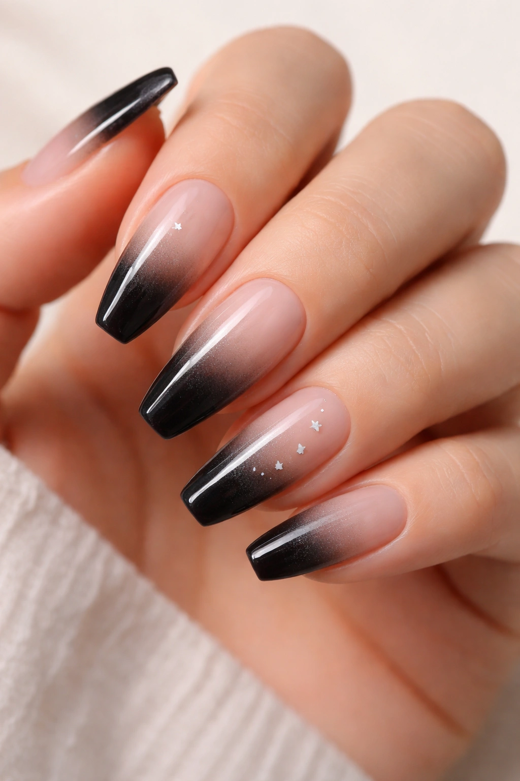 Black-to-clear fade nails with tiny star accents on ballerina nails