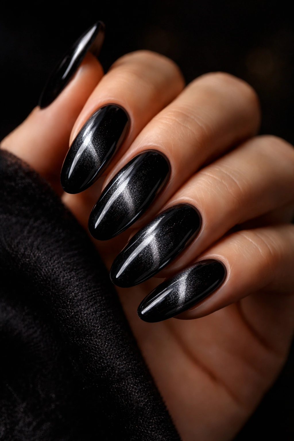 Close-up of black velvet oval nails with magnetic shimmer