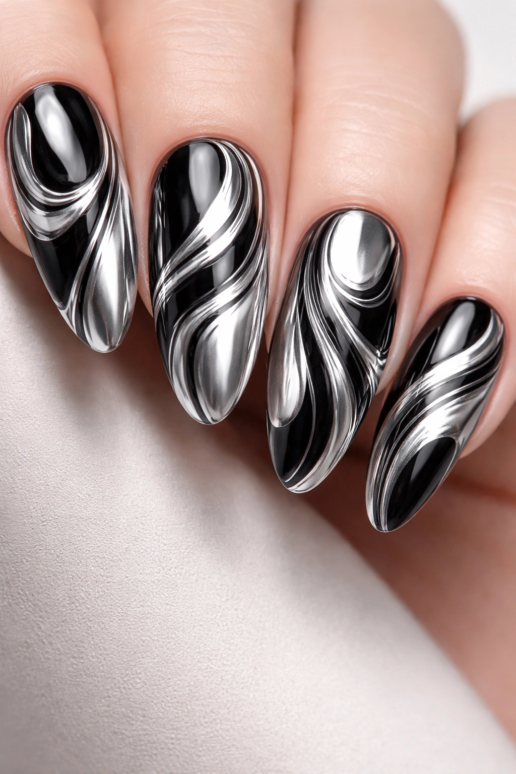Close-up of nails with black and white chrome swirl patterns, highly reflective