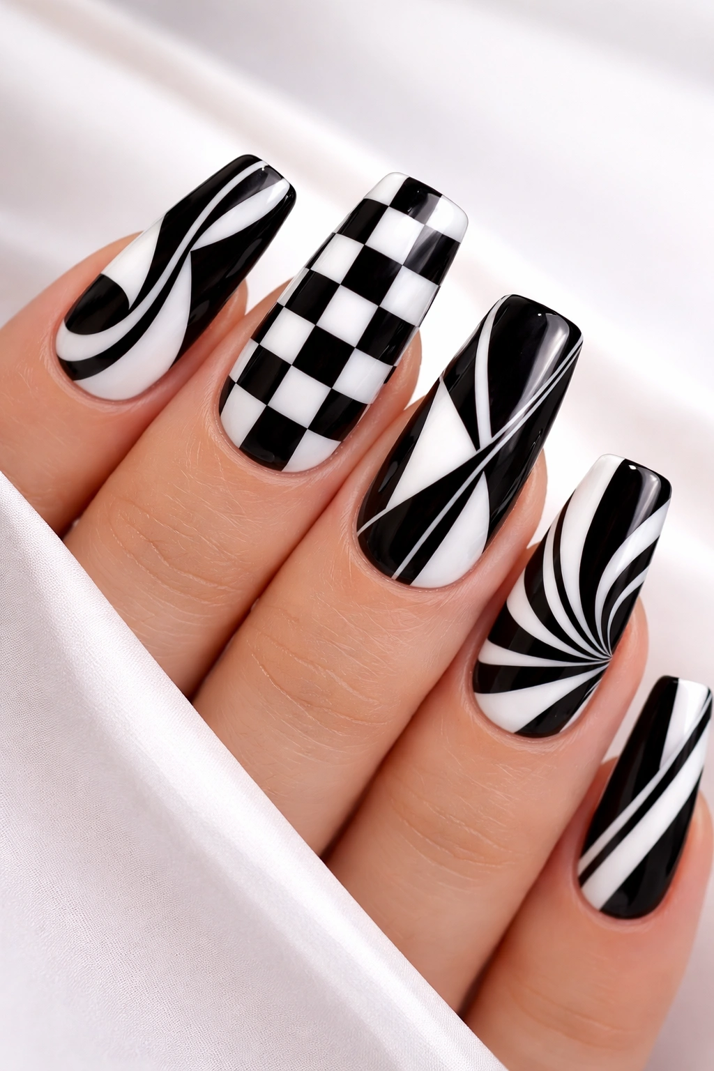 Close-up of long squoval nails with bold black and white geometric patterns