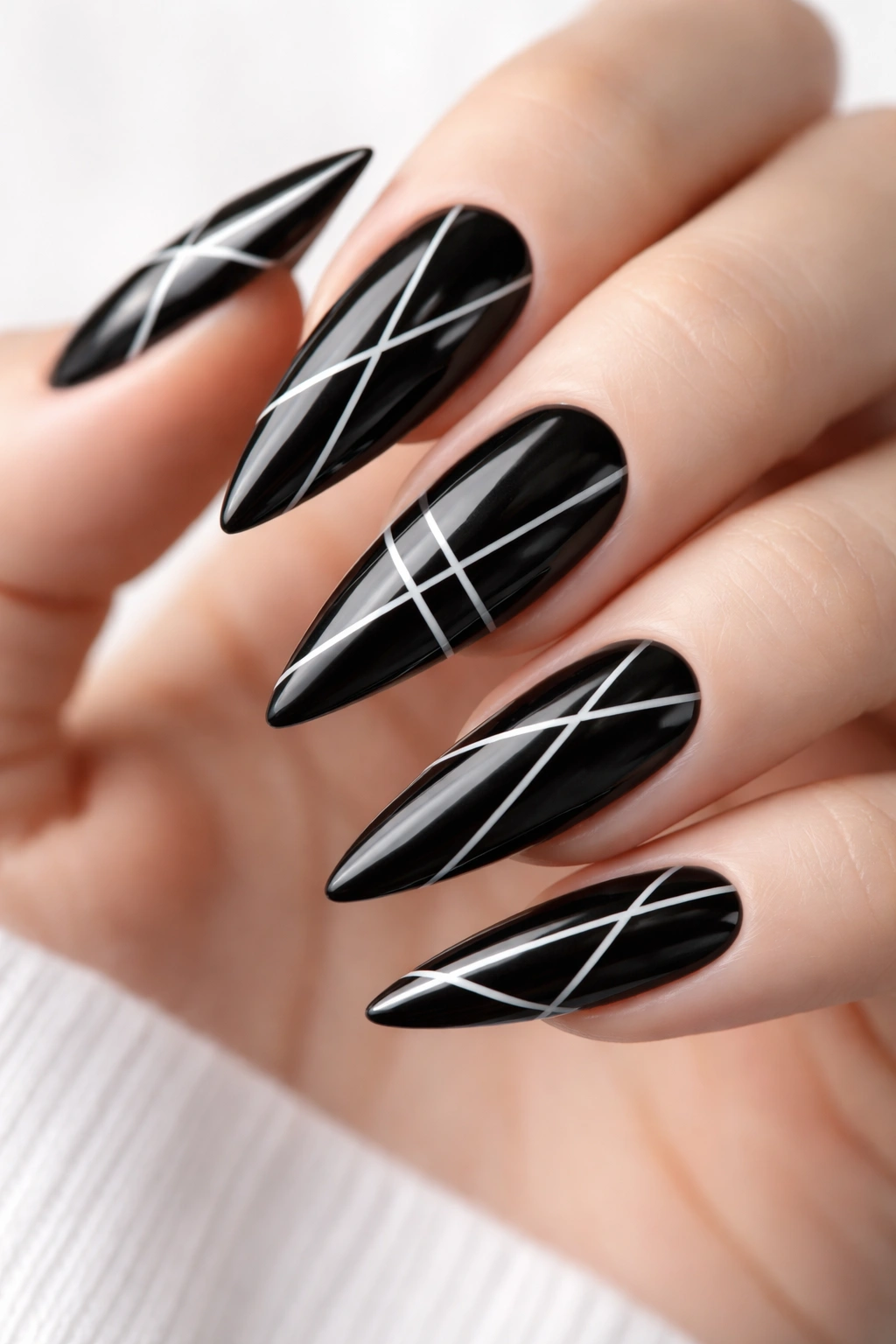 Close-up of black nails with thin white geometric stripes