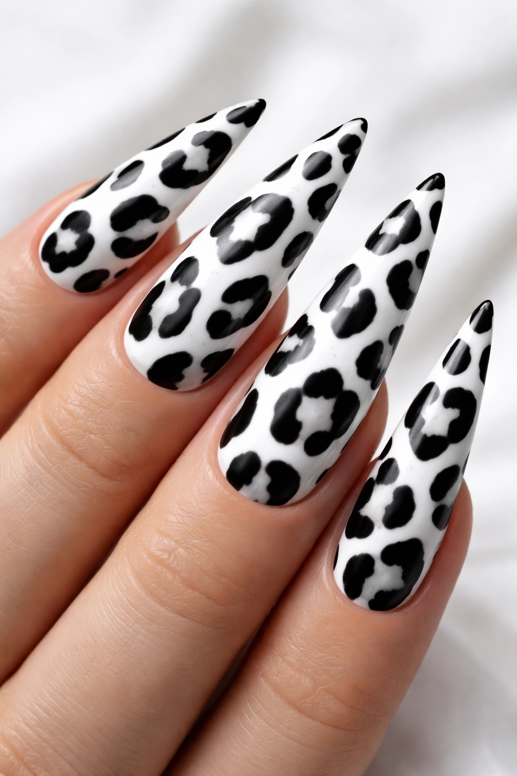 White stiletto nails with black leopard spots in high contrast