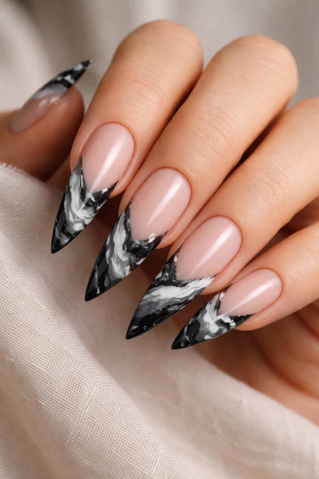 Stiletto nails with black and white marble tips on a nude base