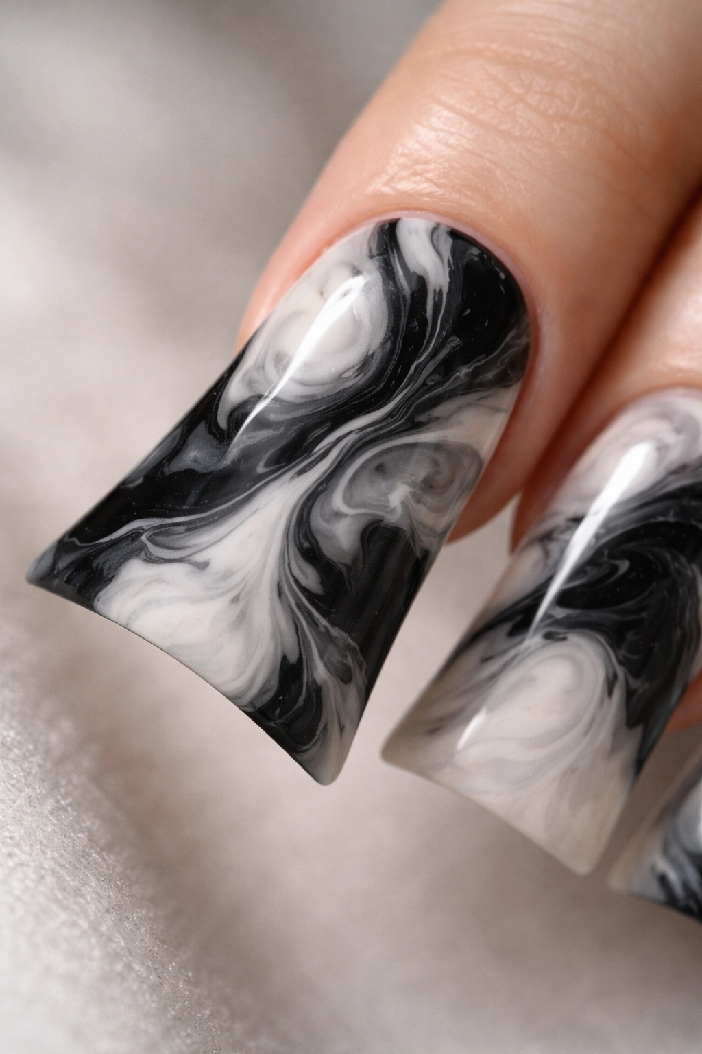 Close-up of a duck nail with black and white marble pattern on the wide tip