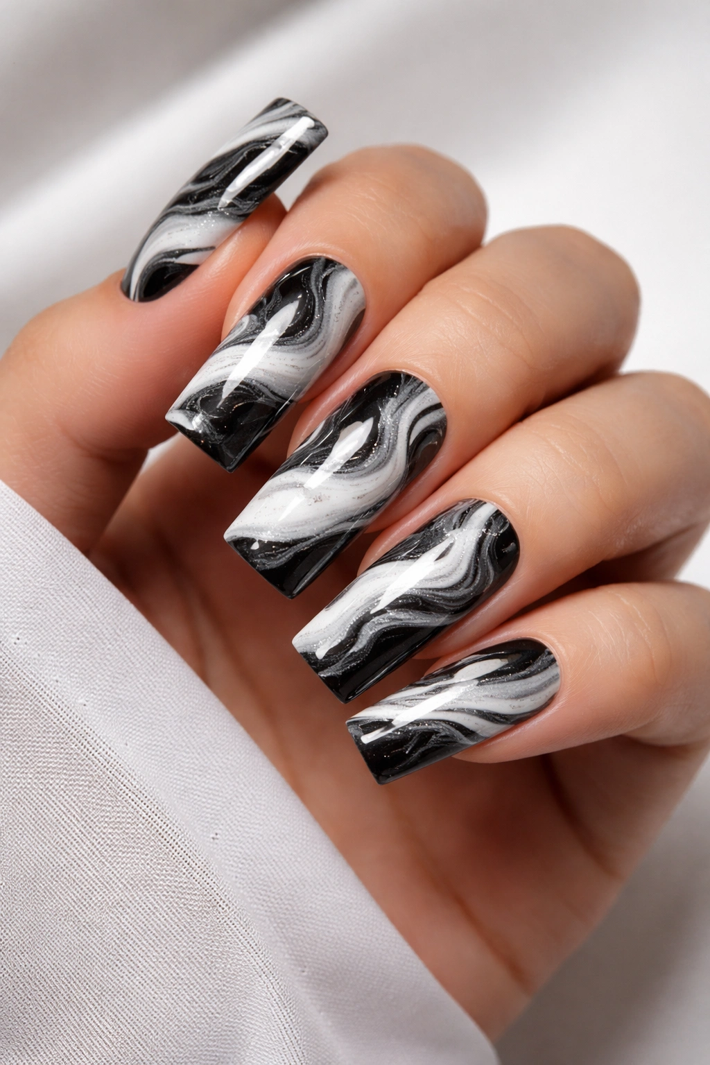 Close-up of square acrylic nails with black and white marble swirls