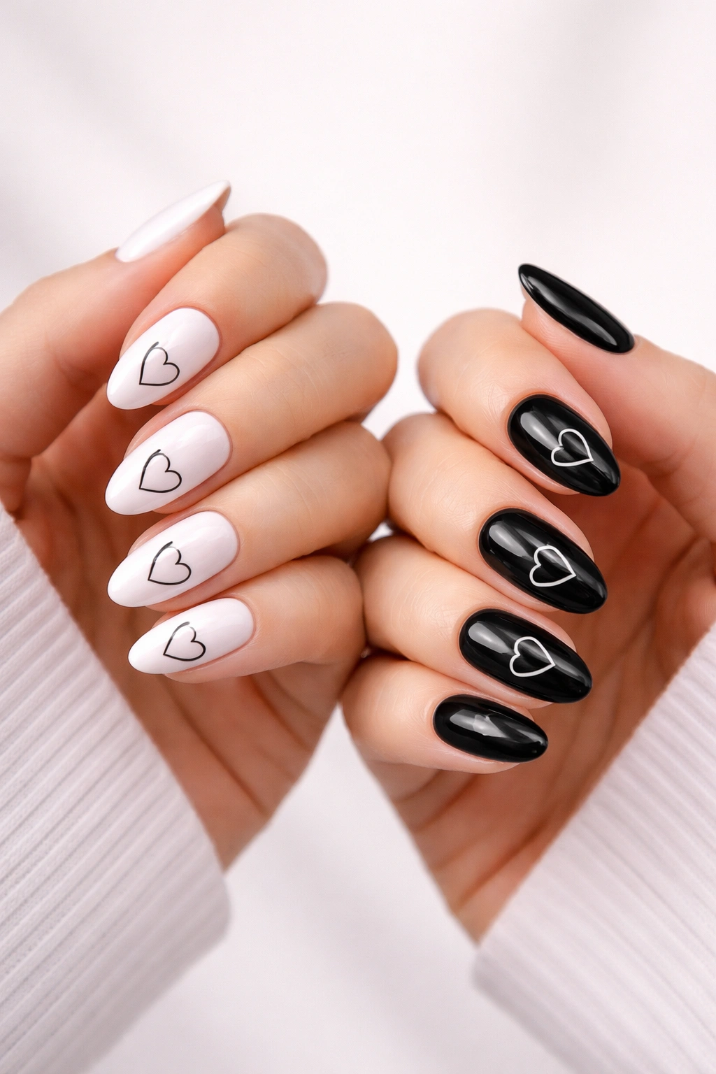 Two hands with black and white minimalist heart nail designs