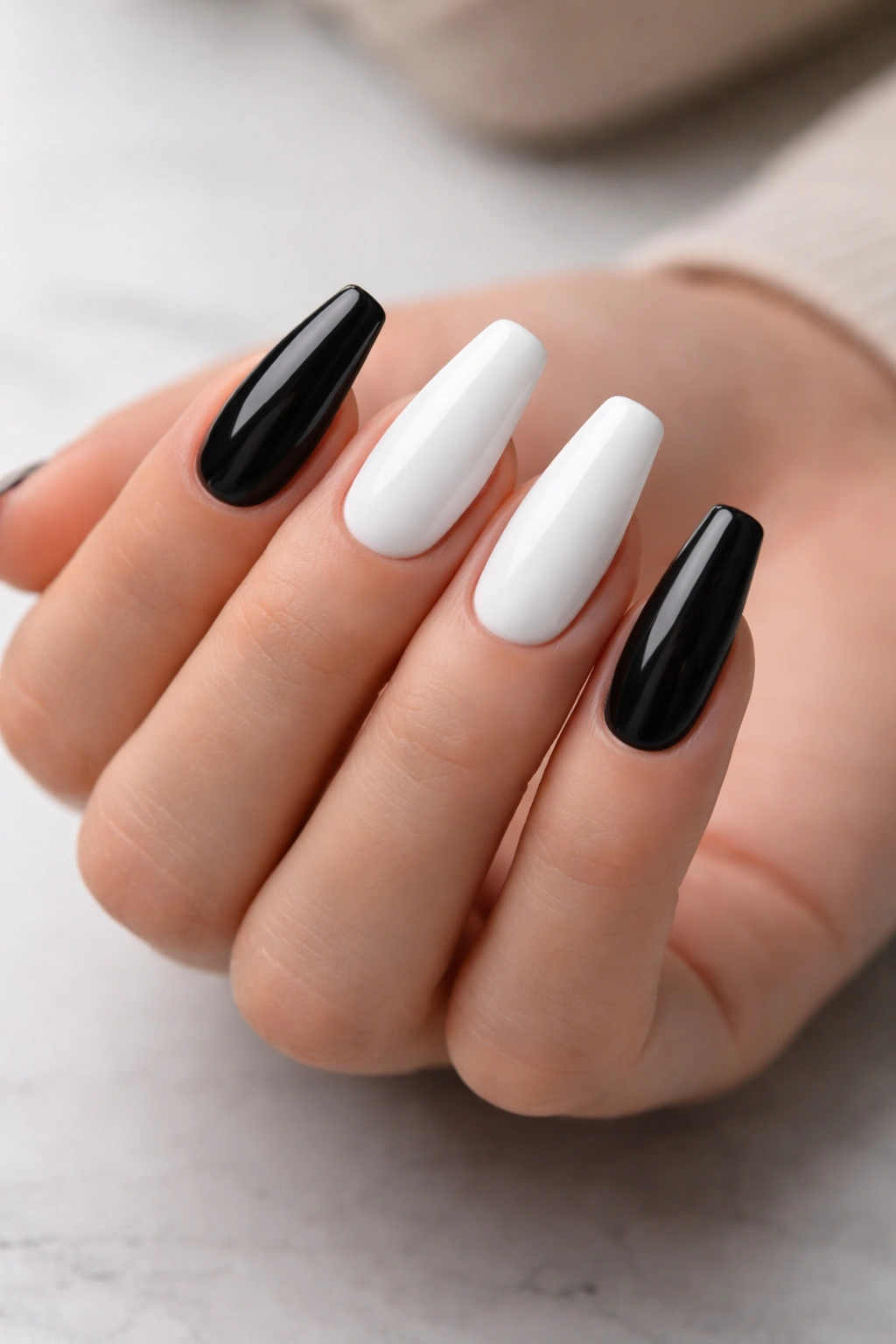Medium-length black and white ballerina nails with crisp tapered sides on a hand