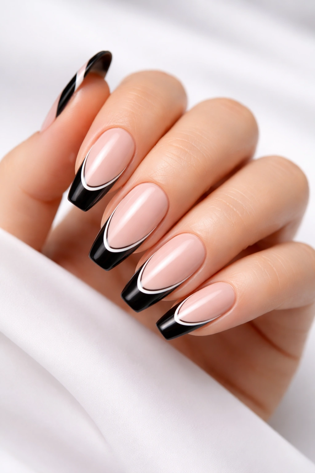 Close-up of hand with black tips outlined in white on nude base