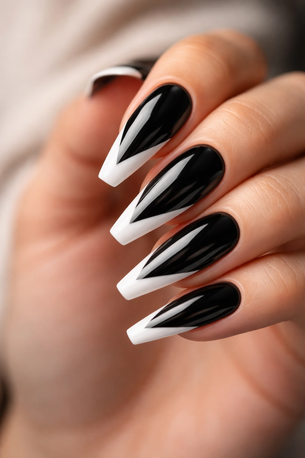 Glossy black nails with white V tips on a ballerina shape