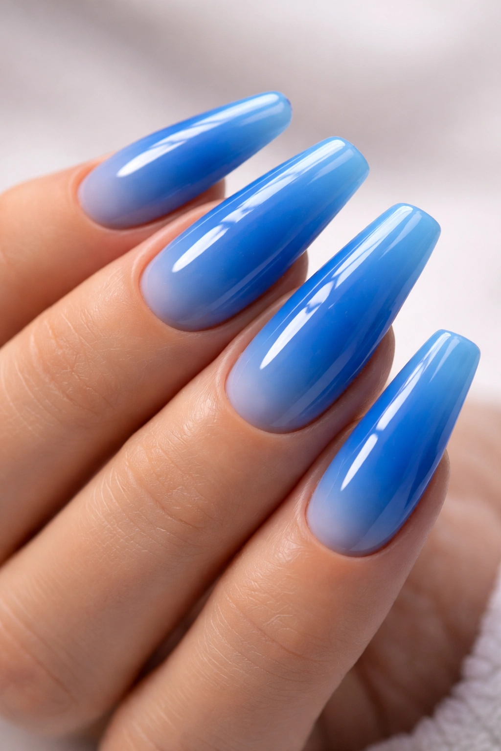 Close-up of blue acrylic nails with glossy finish on fingertips