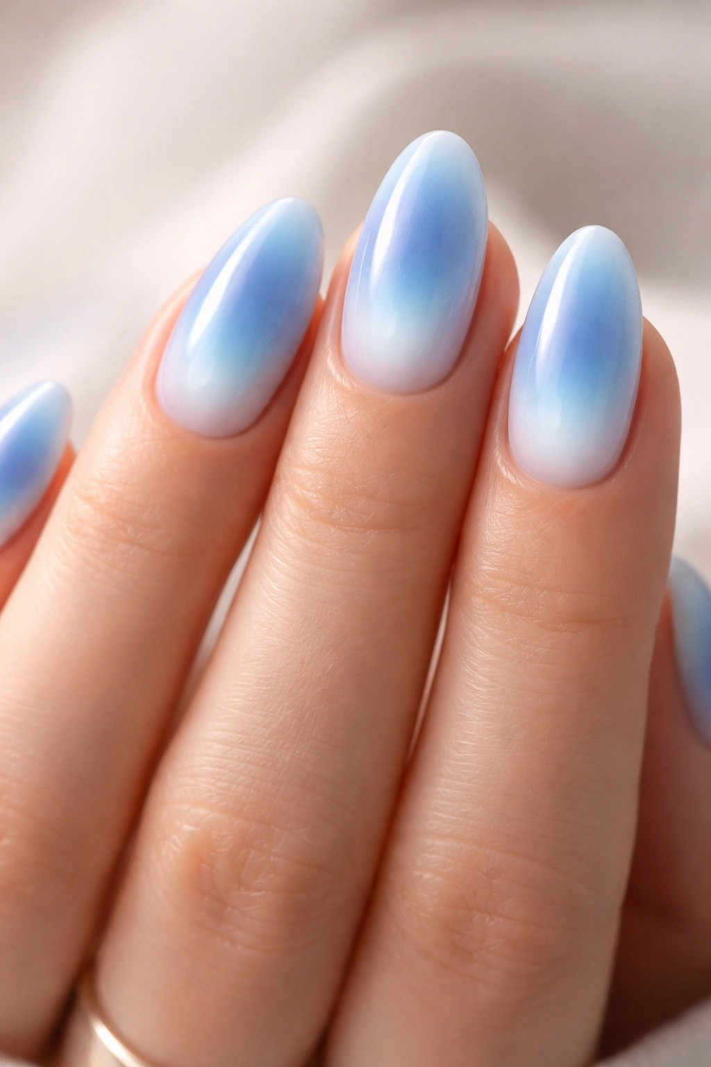Close-up of blue aura nails with a soft halo center on short almond nails