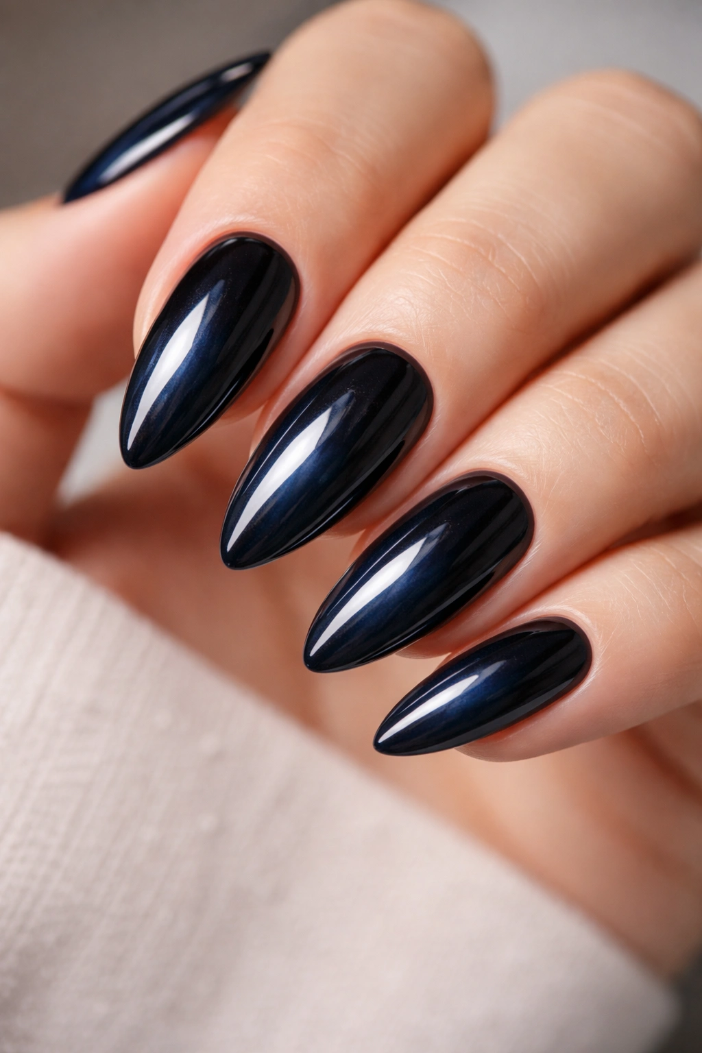 Almond nails in blue-black shade with glossy finish and blue undertone