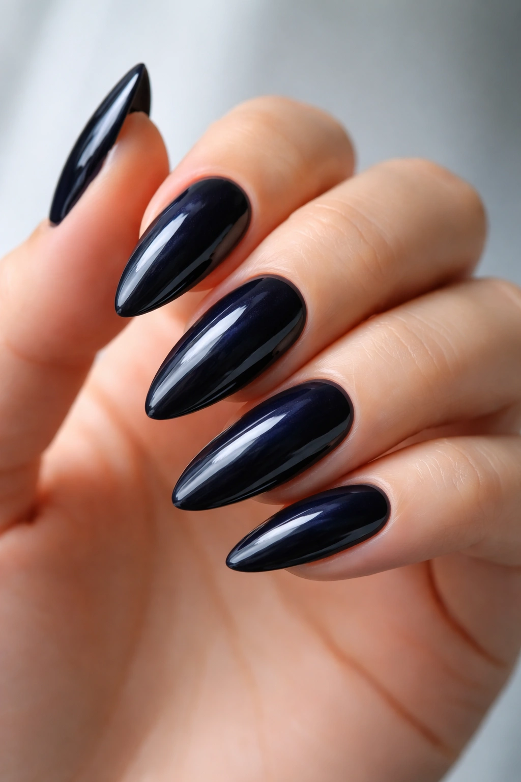 Close-up of almond nails in ink blue-black shade with blue undertone