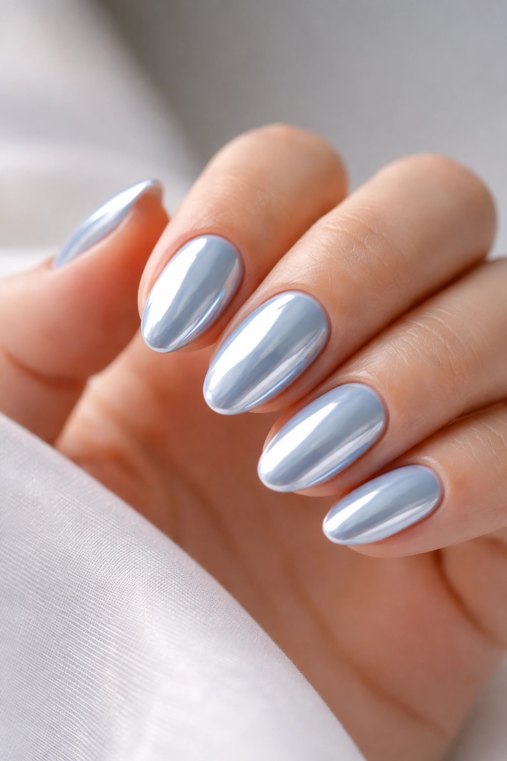 Close-up of baby blue chrome on short almond tips