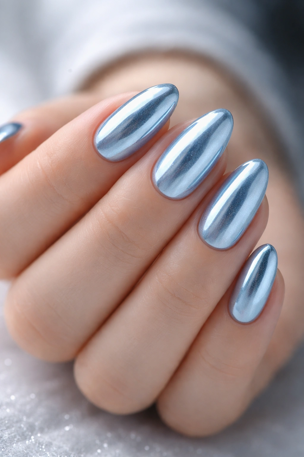 Close-up of short almond nails with blue chrome ice finish