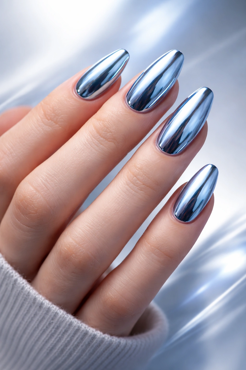 Close-up of hand with metallic blue chrome nails under cool lighting