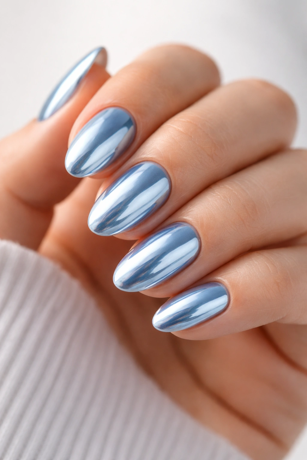 Close-up of short almond nails with icy blue chrome finish