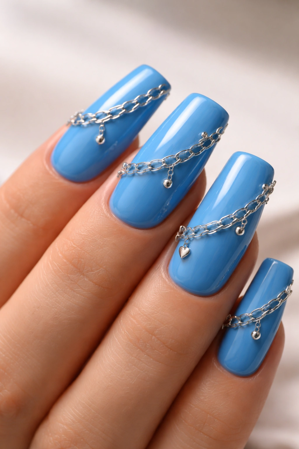 Close-up of blue duck nails featuring chain link accents for edgy texture
