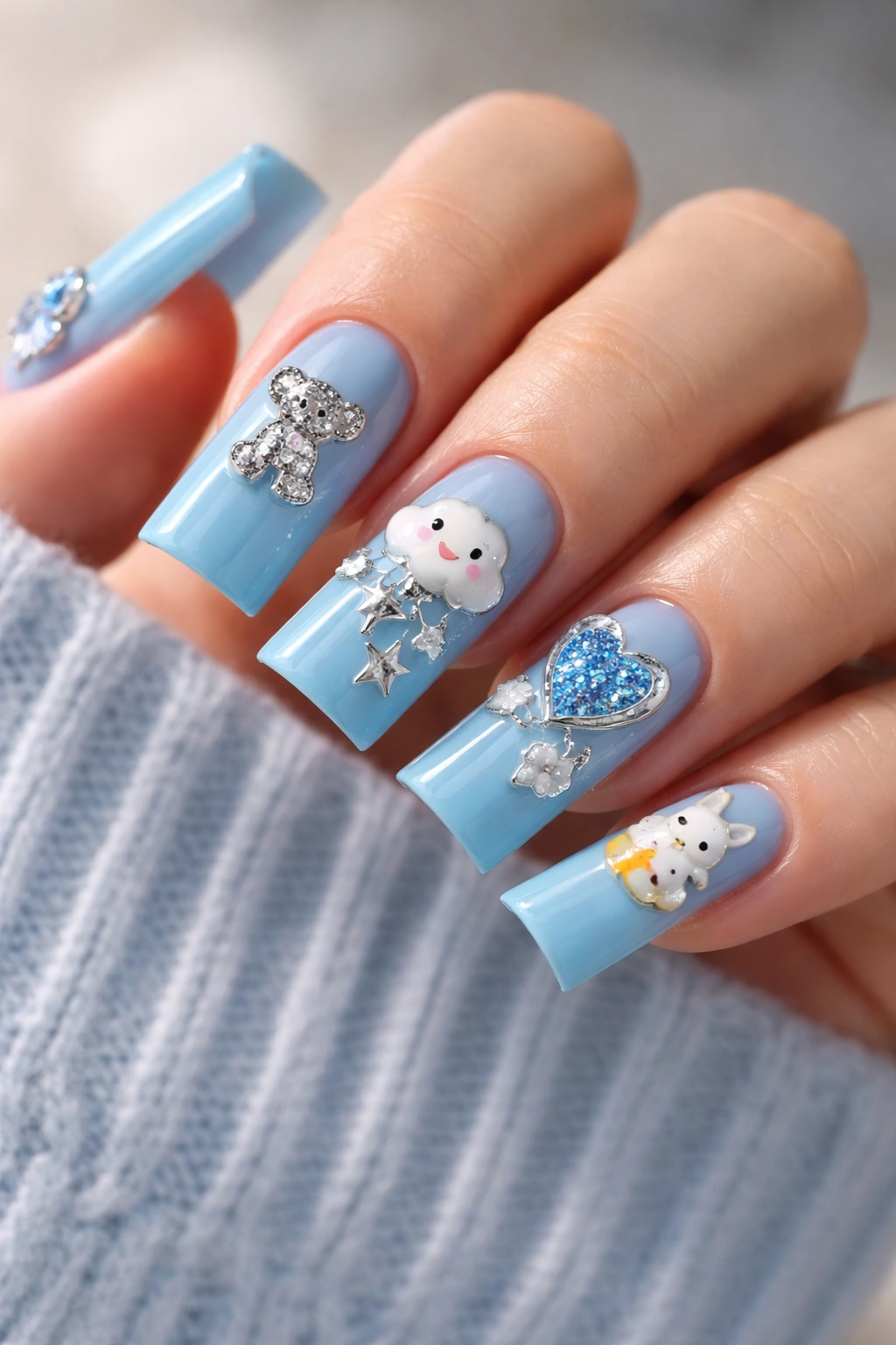 Close-up of blue duck nails with enamel charms integrated into the design