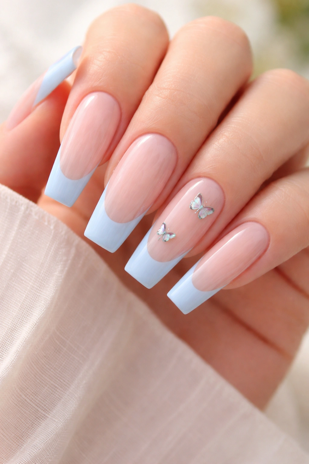 Baby blue French tips with tiny butterfly decals on long ballerina nails.