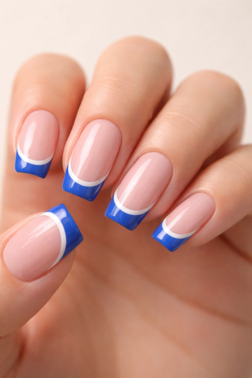 Close-up of nude-based nails featuring crisp blue and white French tip manicure