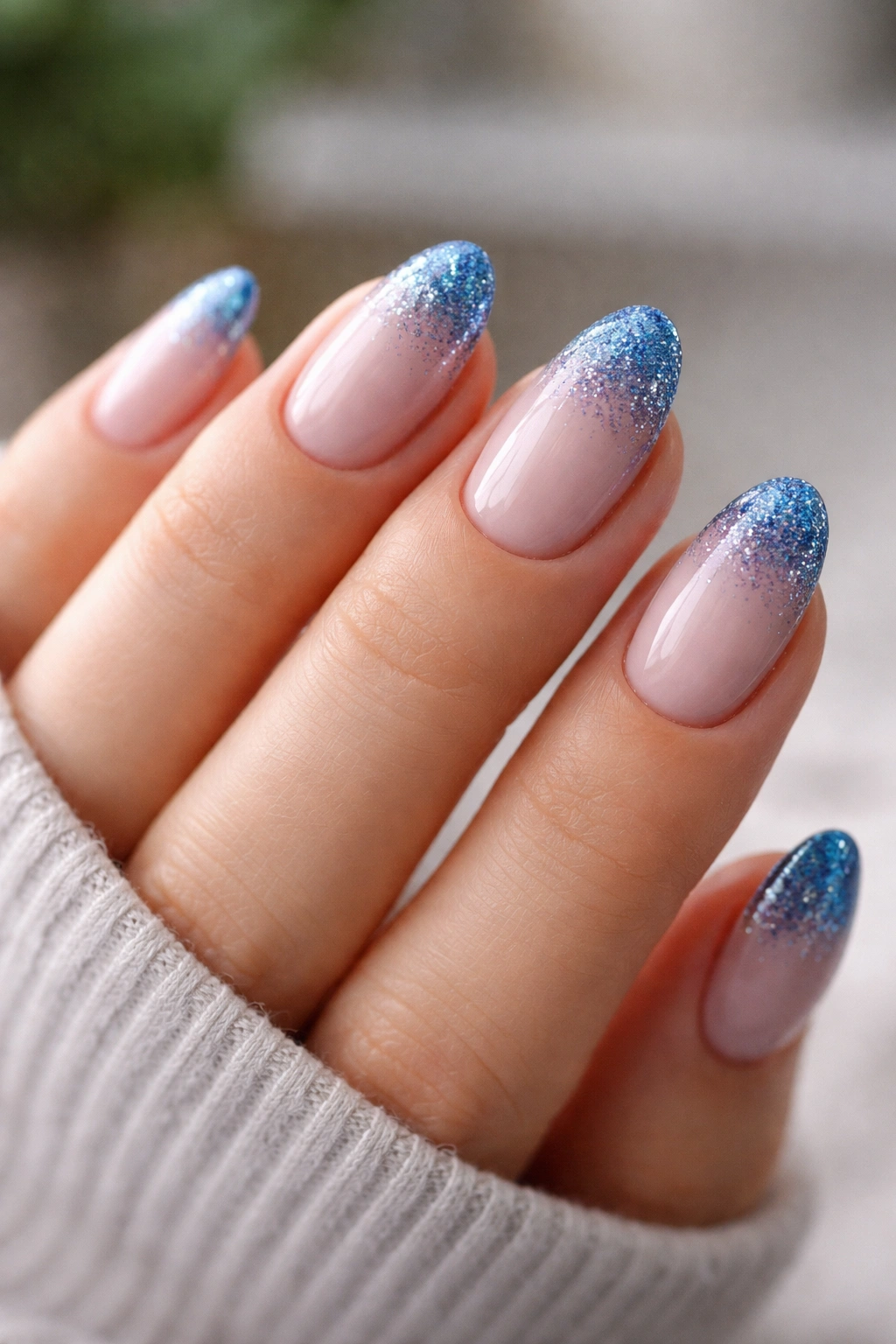 Short almond nails with blue glitter tips on a nude base