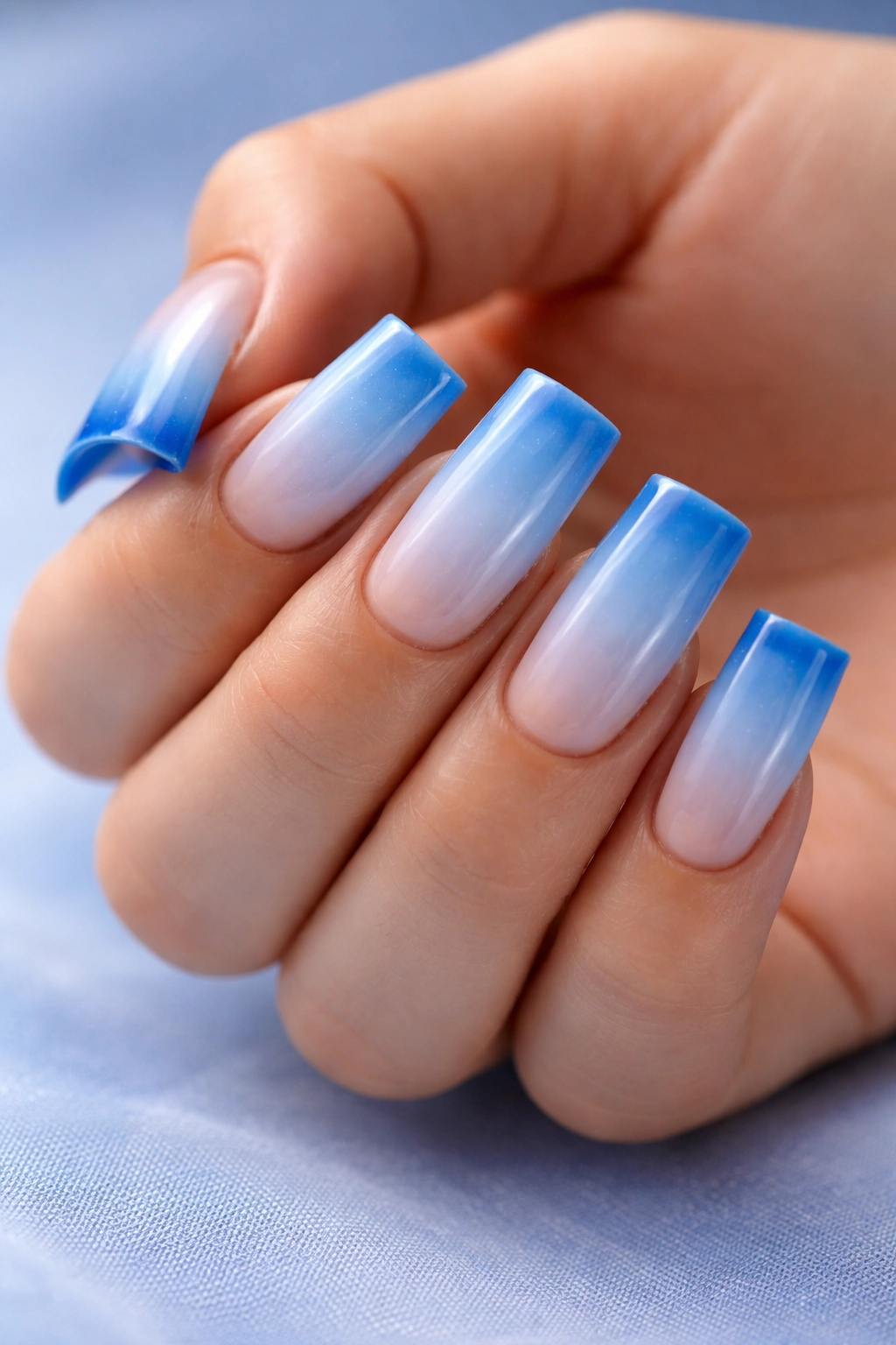 Close-up of blue gradient duck nails on a hand