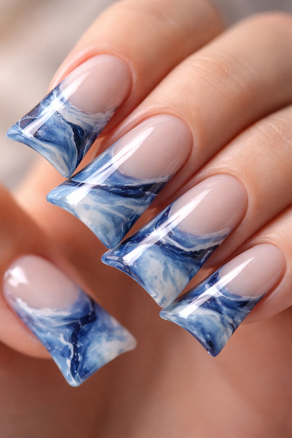 Blue marble pattern on duck nails with curved tips.